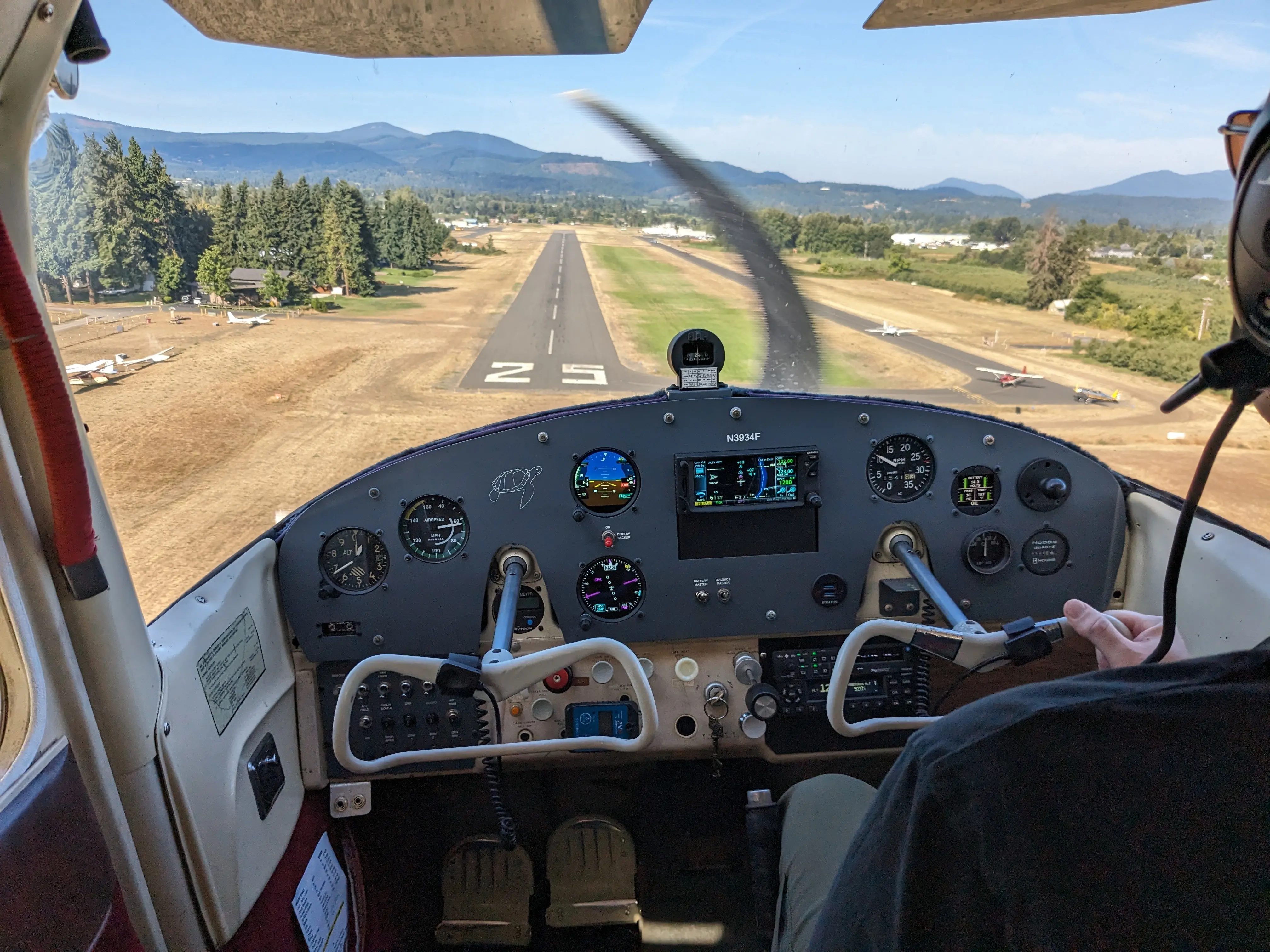 GWA's Cessna 172 landing on Hood River Airport's paved runway. The grass runway is also visible. The view is from inside of the 172's cockpit.
