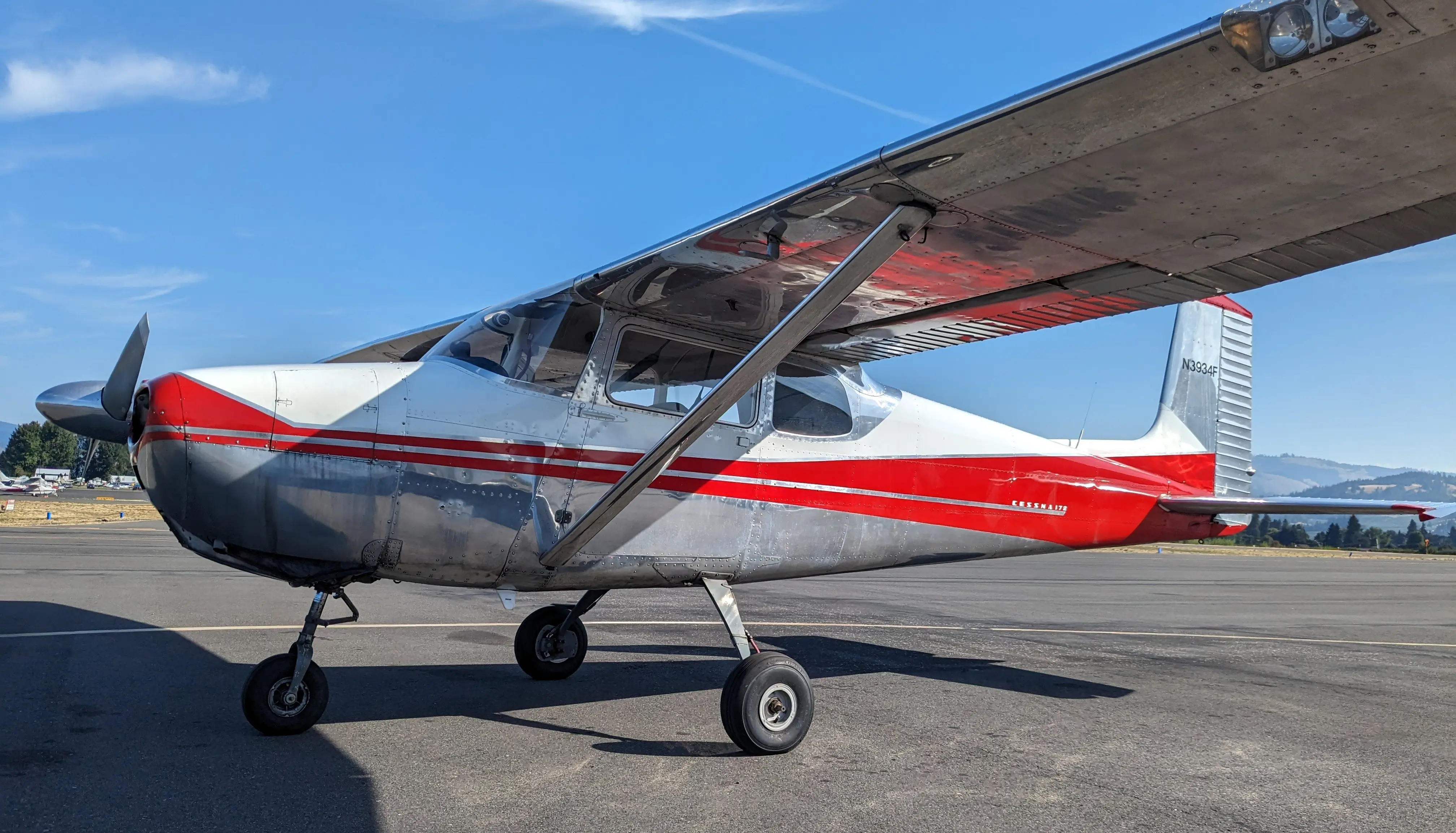 GWA's Cessna 172, parked at the Hood River airport. It is a silver airplane with bright red detailing.